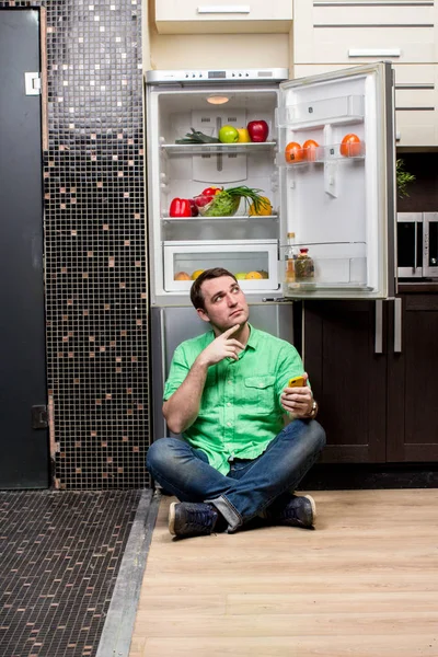 若い男は冷蔵庫の前に座って — ストック写真