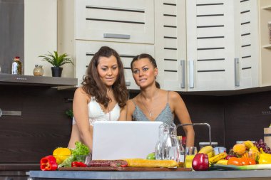 İki çekici kadın laptop, kitche ayakta arayan İkizler