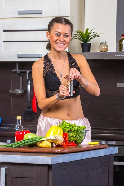 Ung kvinna krydda grönsakssallad med salt eller peppar på hom — Stockfoto
