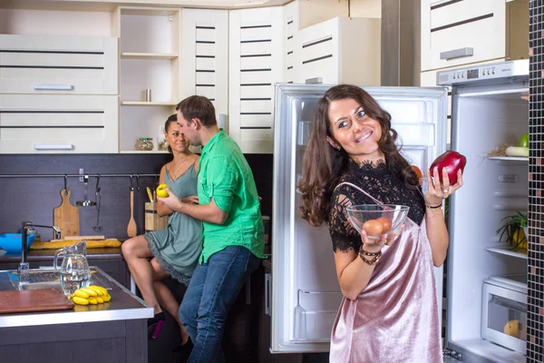 Kvinna som tittar till kylskåp med par på bakgrund. — Stockfoto