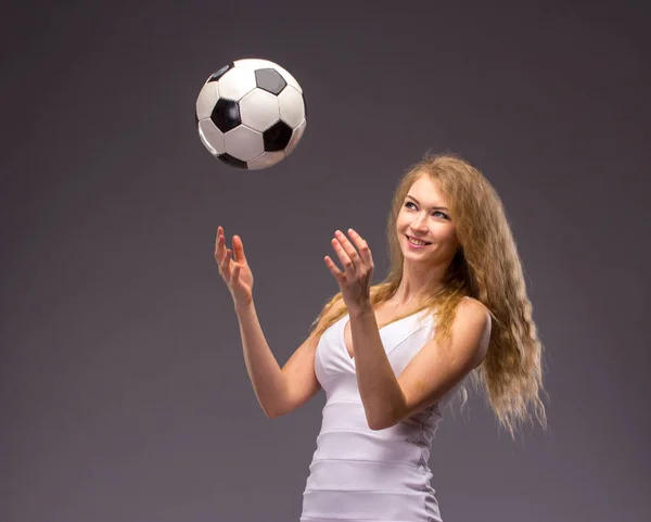 Молода жінка в білому вечірньому платті з футбольним м'ячем — стокове фото