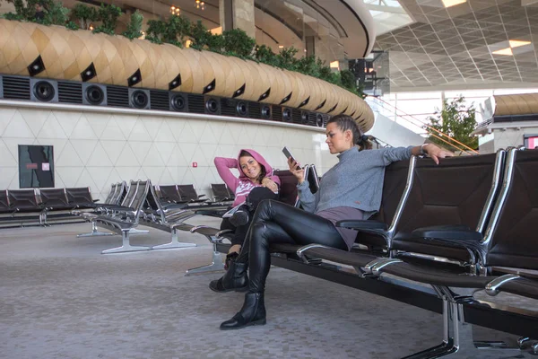 Mujer gemela sentada en el salón del aeropuerto —  Fotos de Stock