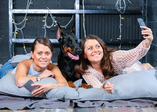 Tvillingar gör selfie i sängen med stor hund — Stockfoto