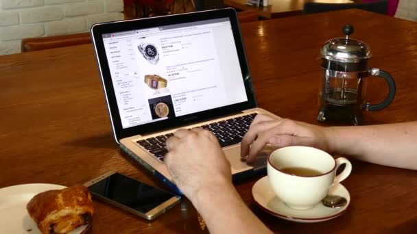 Homem visita site aliexpress usando MacBook Pro laptop pc no café — Vídeo de Stock