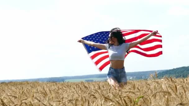 美丽的女孩运行上黄色麦田与我们国旗. — 图库视频影像