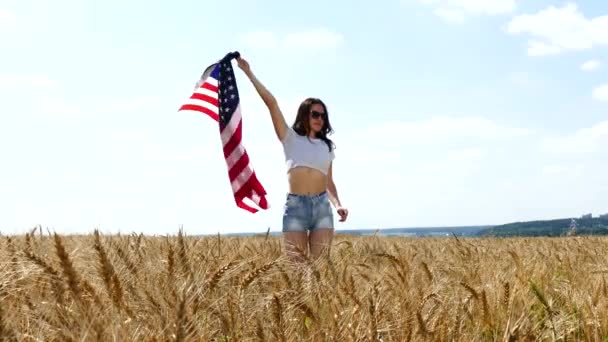 Beauté fille courir sur le champ de blé jaune avec drapeau national américain . — Video