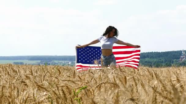 Beauté fille courir sur le champ de blé jaune avec drapeau national américain . — Video