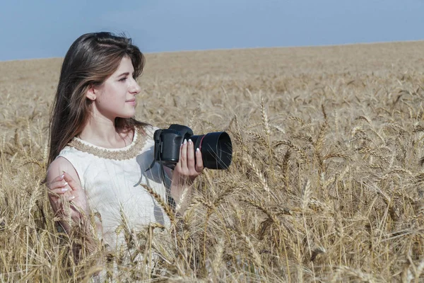 Vacker flicka att ta bilder med stor svart kamera på fältet — Stockfoto
