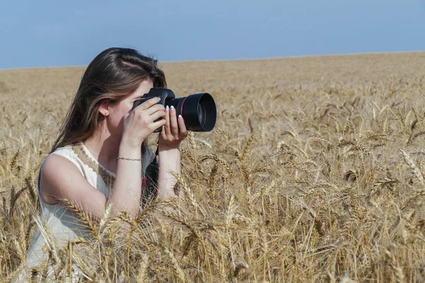 Mooi meisje fotograferen met grote zwarte camera op het veld — Stockfoto