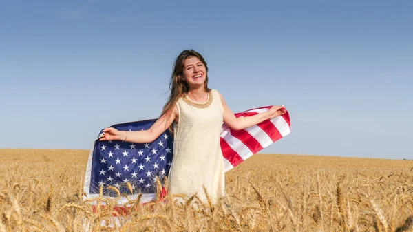 Hermosa chica con una bandera de Estados Unidos en el campo — Foto de Stock