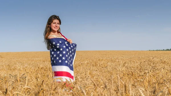 Mooi meisje met een Amerikaanse vlag op het gebied — Stockfoto