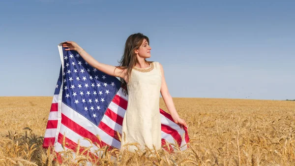 Hermosa chica con una bandera de Estados Unidos en el campo — Foto de Stock