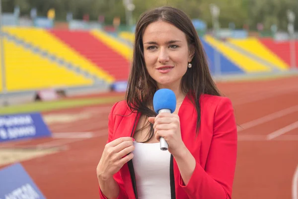 Pretty journalist is reporting from the stadium for television — Stock Photo, Image