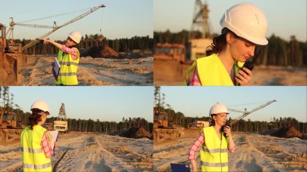 Bella donna in casco discute qualcosa di walkie talkie con enorme escavatore sullo sfondo — Video Stock