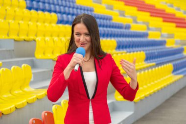 The journalist is reporting from the stadium for television clipart