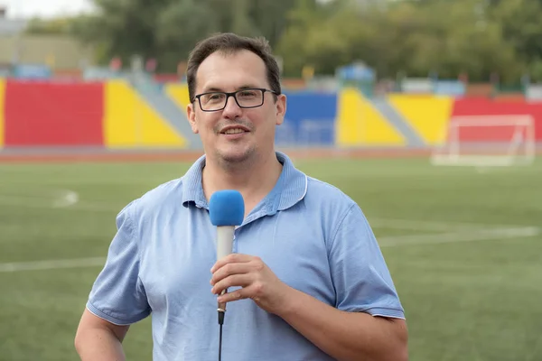 The journalist is reporting from the stadium for television