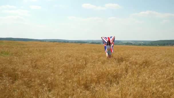 Menina de beleza correndo no campo de trigo amarelo com bandeira nacional dos EUA. Mulher feliz ao ar livre. Colheita — Vídeo de Stock