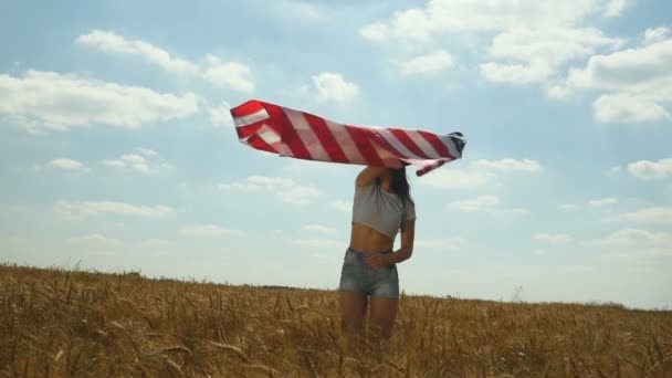 Девушка-красавица бежит по желтому пшеничному полю с национальным флагом США. Счастливая женщина на улице. Урожай — стоковое видео