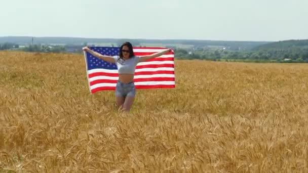 Skönhet flicka kör på gula vetefält med oss flagga. Lycklig kvinna utomhus. Skörd — Stockvideo