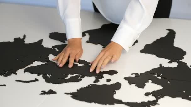 Women's hands touch the parts of the world map on the desk in the office — Stock Video