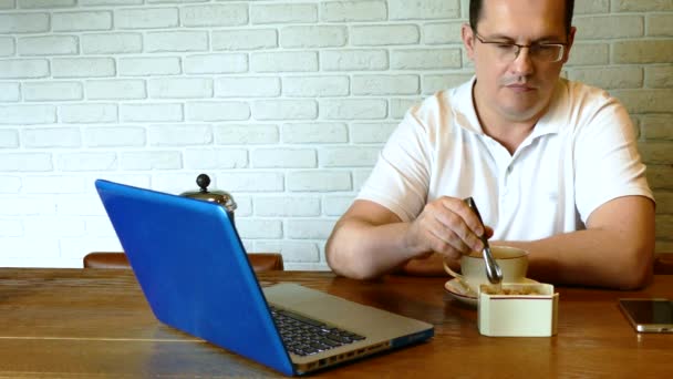 Muž pít čaj v kavárně s notebookem na stole — Stock video