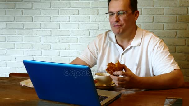 Hombre bebiendo té en la cafetería con el ordenador portátil en la mesa — Vídeo de stock