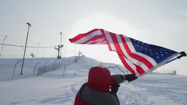 Человек с флагом США на лыжном склоне — стоковое видео