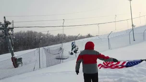 Hombre con bandera estadounidense en una pista de esquí — Vídeos de Stock