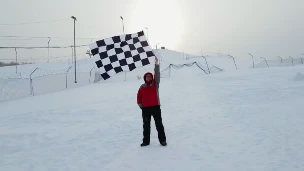 Человек с финишным флагом на лыжном склоне — стоковое видео