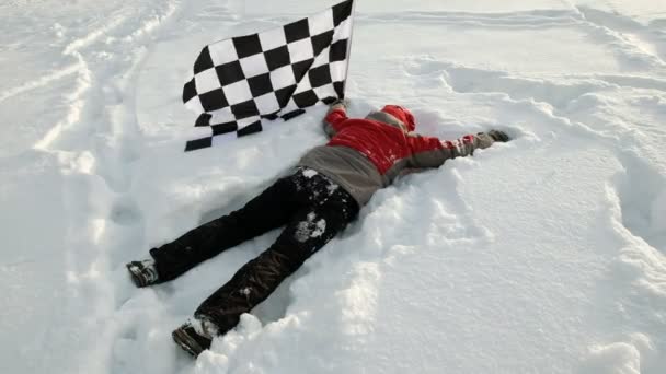男人挥舞着一只完成的片状旗帜躺在雪地里 — 图库视频影像