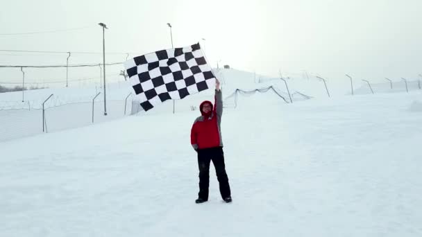 Человек с финишным флагом на лыжном склоне — стоковое видео