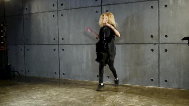 Mujer en ropa negra baila en estilo moderno sobre zócalo cerca de gran ventana — Vídeo de stock