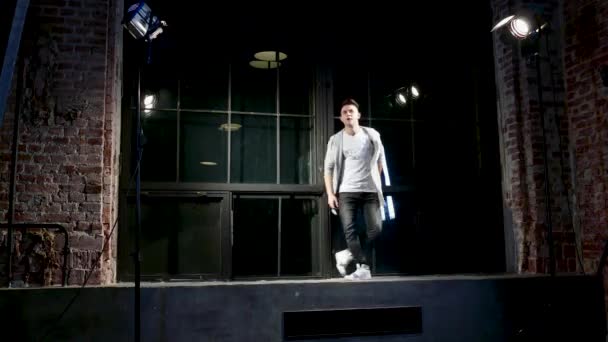 Mann in schwarzer Kleidung tanzt modern auf Sockel neben großem Fenster — Stockvideo