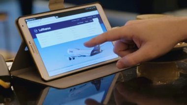 15 Şubat, FRANKFURT, GERMANY: Adam kafedeki tablet bilgisayarla Lufthansa havayolları şirketinin sitesine giriyor. İnternetten alışveriş.