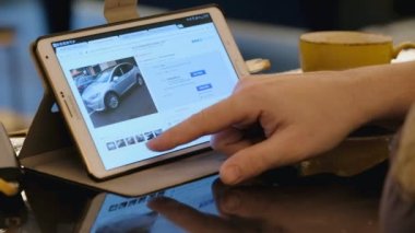 Adam seyir için ebay sitesi keşfetmek kafede tablet pc kullanarak Tesla ikinci el araç.