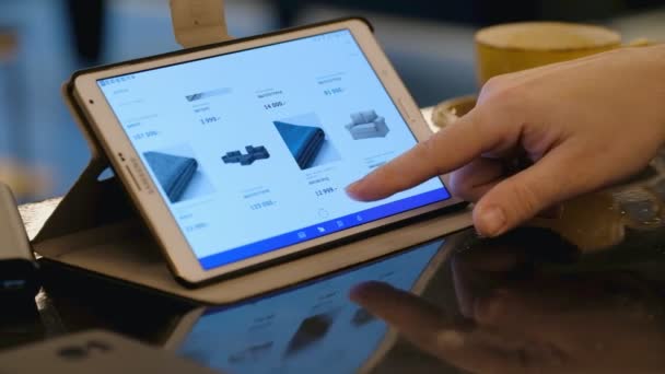 Muž zkoumání Ikea webu hledáte nábytek pomocí počítače tablet pc v kavárně. — Stock video