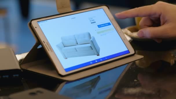 Muž zkoumání Ikea webu hledáte nábytek pomocí počítače tablet pc v kavárně. — Stock video