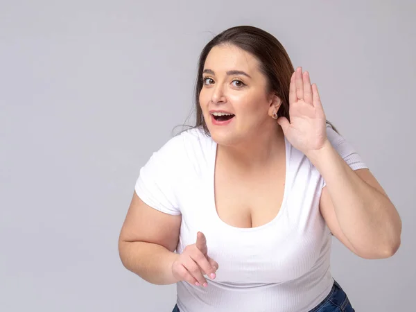 Shocked Plus Size Model with long hair posing in studio. Listening with hand to ear. — Stock Photo, Image