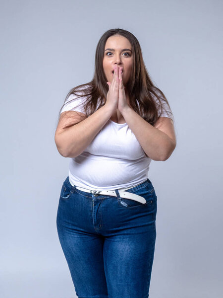 Shocked Plus Size Model с длинными волосами позирует в студии
