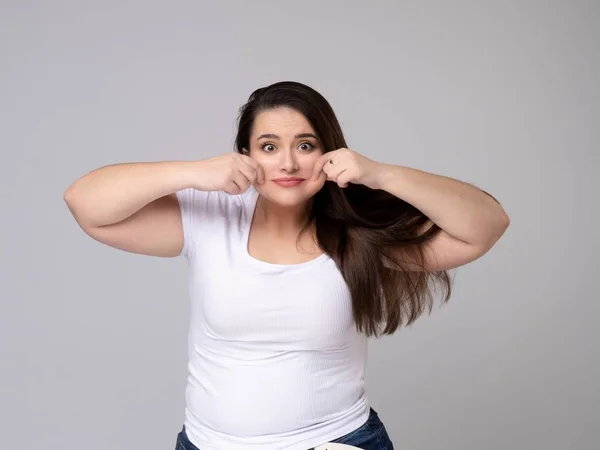 Plus Size Model met lang haar Grimmig, trekken aan haar wangen. — Stockfoto