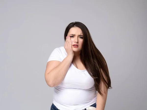 Modelo Plus Size com uma mão segurando um dente dolorido — Fotografia de Stock