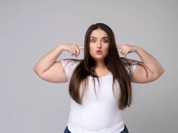 Aggressive Plus Size Model covers ears with fingers. — Stock Photo, Image