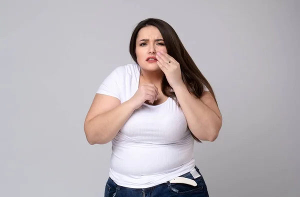 Modelo Plus Size com uma mão segurando um dente dolorido — Fotografia de Stock