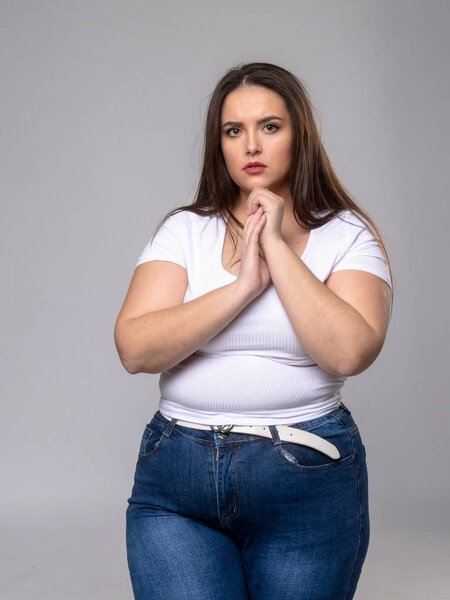Модель размера грустный плюс с длинными волосами позирует в студии
