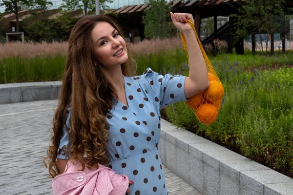 Joven mujer positiva sosteniendo naranjas —  Fotos de Stock