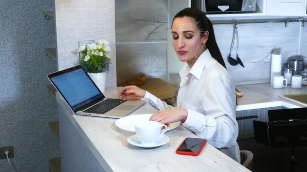 Glædelig spansktalende kvinde færdig med at arbejde på bærbar computer i køkkenet – Stock-video