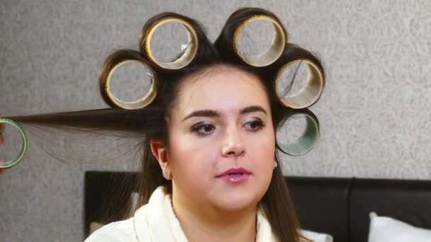 Friseurin zieht Lockenwickler an Frau mit langen Haaren an — Stockvideo