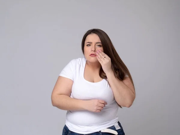 Modelo Plus Size com uma mão segurando um dente dolorido — Fotografia de Stock