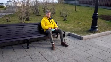Sick man take on medical mask sitting on a park bench