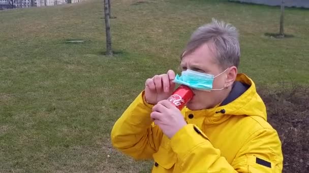 Hombre enfermo en máscara médica bebe coca al aire libre — Vídeo de stock